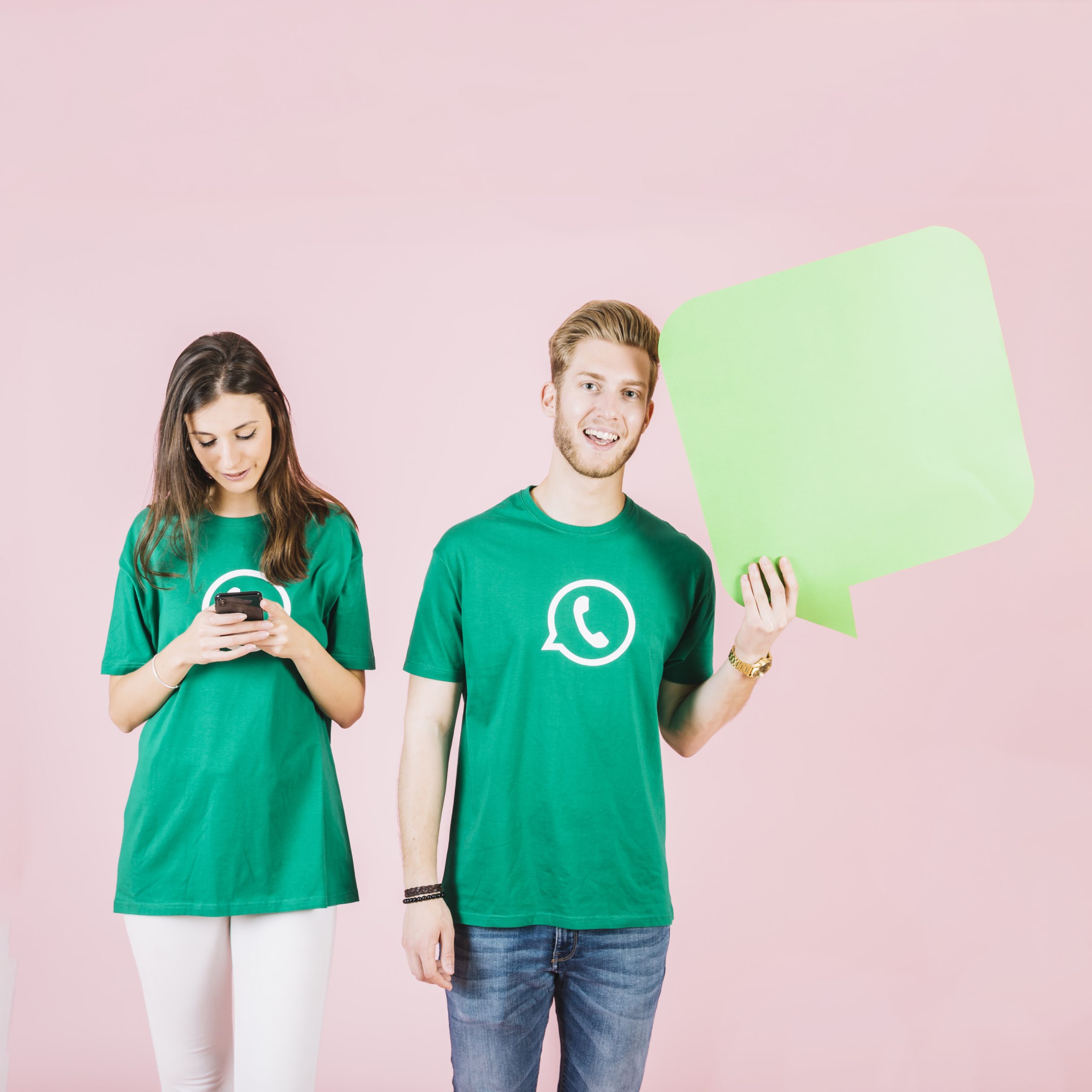 smiling-young-man-holding-speech-bubble-beside-woman-using-smartphone
